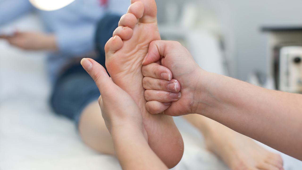 Daumen drücken auf die Fußsohle einer Patientin