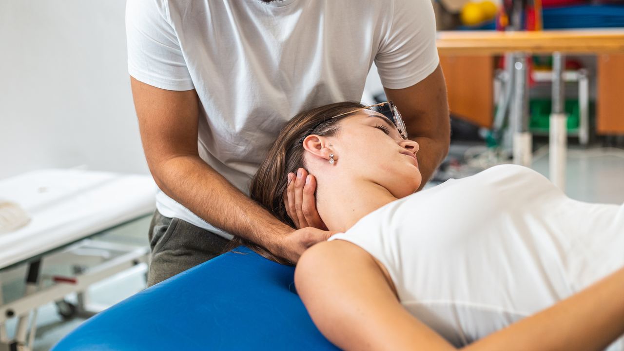 Therapeut hält Kopf und Nacken einer seitlich liegenden Patientin